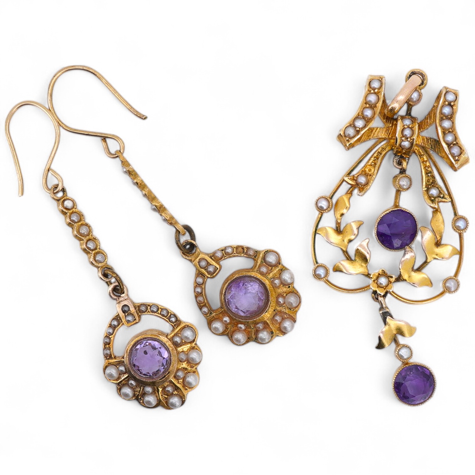 An amethyst and seed pearl demi-parure, early 20th century, comprising: a pendant of foliate design surmounted by a bow, set with oval amethysts and seed pearls, mounted in gold, length 5.2cm, and a matched pair of ameth